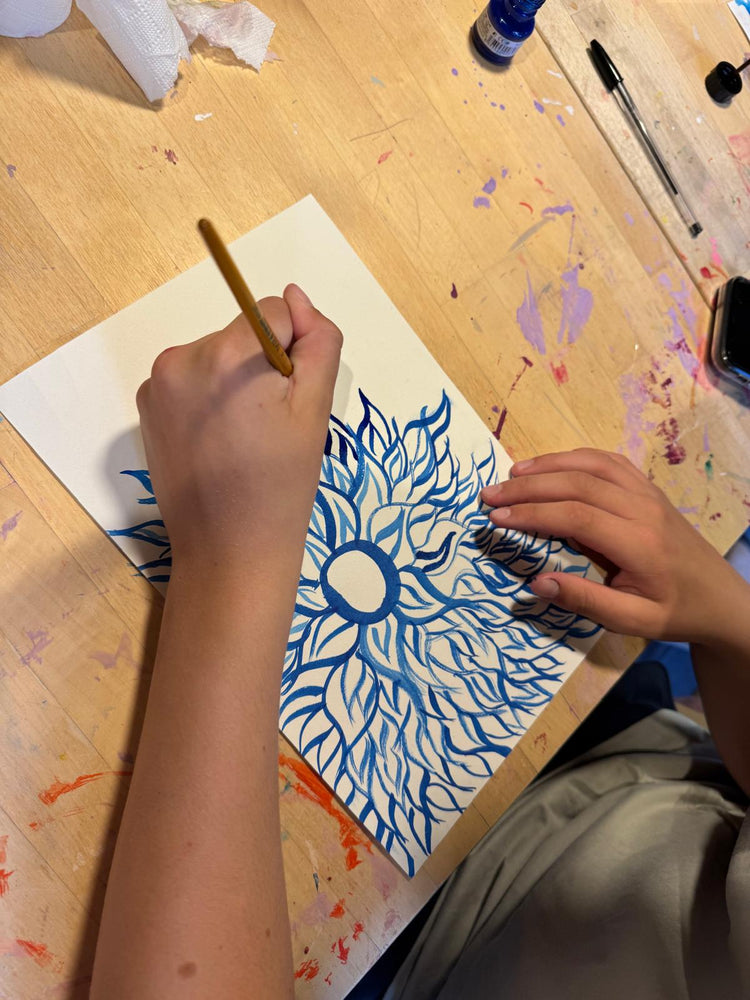 Child painting a blue sun artwork